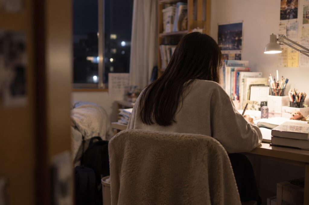 夜、机に向かって受験勉強をする学生の後ろ姿