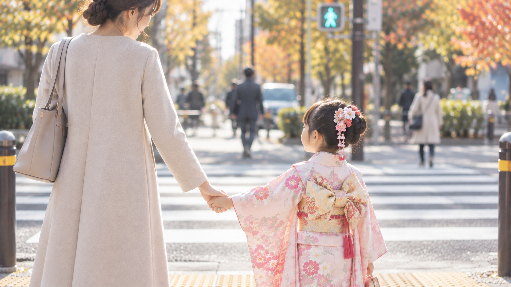 紅葉の街の横断歩道で、着物姿の娘と手をつないで歩く母親の後ろ姿